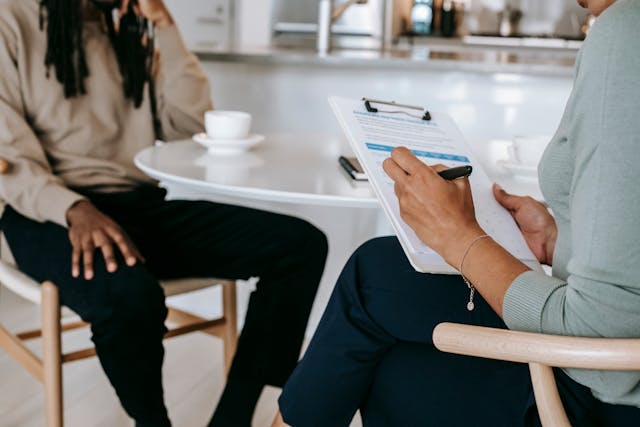 Person with a clipboard sitting at a table across from another person